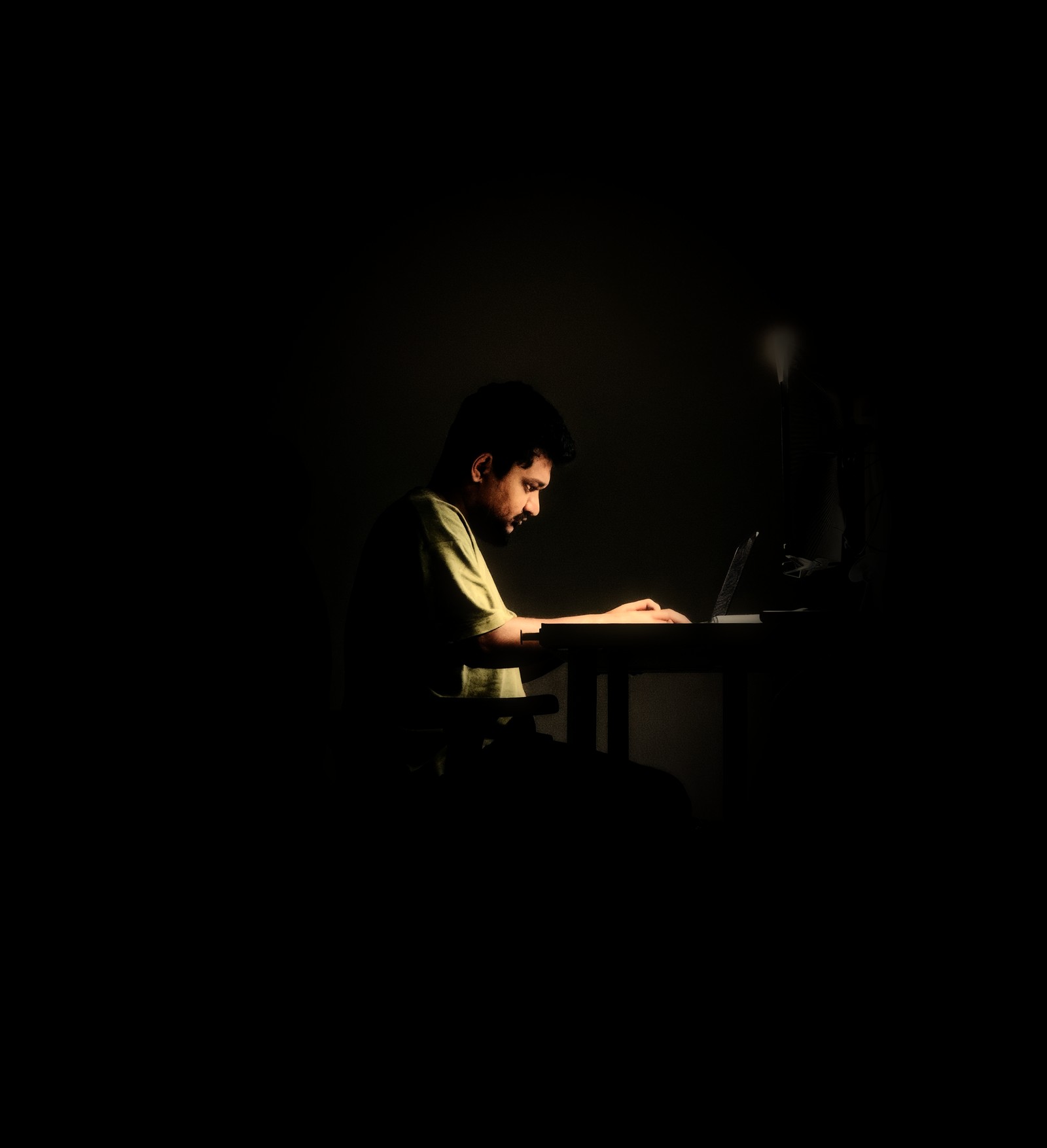 Jayraj Jadeja working at a desk late at night, lit by a single lamp